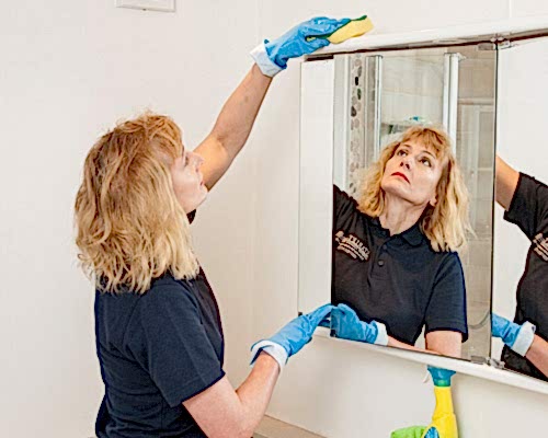 Cleaner wiping a bathroom mirror for One Off Cleaning London